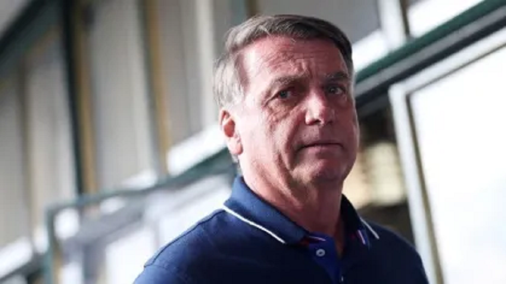 Jair Bolsonaro (PL) sério, sem olhar para a câmera, de camisa polo azul