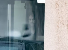 Jair Bolsonaro atrás de vidro na sede da PF, sério