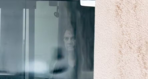 Jair Bolsonaro atrás de vidro na sede da PF, sério