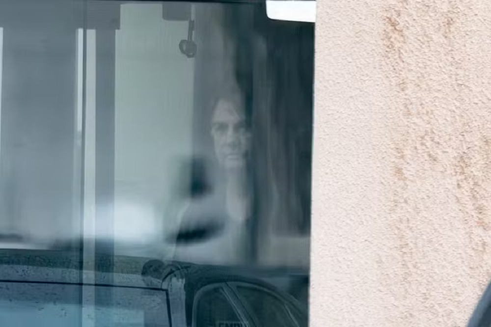 Jair Bolsonaro atrás de vidro na sede da PF, sério