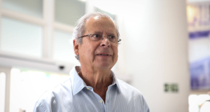 O ex-ministro José Dirceu de camisa social clara e óculos de grau, com expressão pensativa