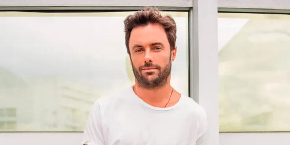 O ator Kayky Brito de camiseta branca, olhando sério para a câmera