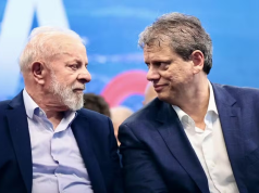 Lula e Tarcísio de Freitas se olhando, sérios, sentados lado a lado