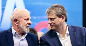 Lula e Tarcísio de Freitas se olhando, sérios, sentados lado a lado