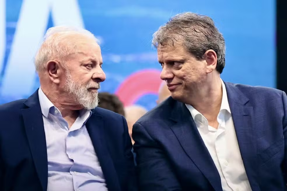 Lula e Tarcísio de Freitas se olhando, sérios, sentados lado a lado