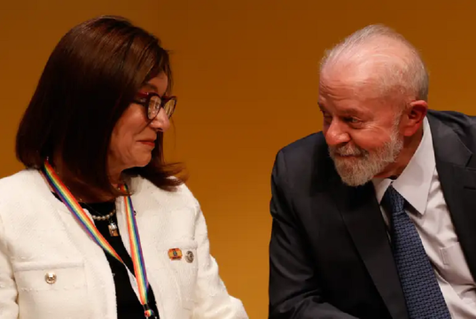 A presidente da Petrobras, Magda Chambriard, e o presidente Luiz Inácio Lula da Silva (PT), se olhando e rindo, sentados lado a lado