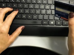 Mãos no teclado e segurando cartão de crédito