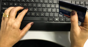 Mãos no teclado e segurando cartão de crédito