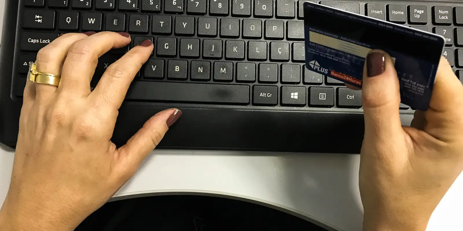 Mãos no teclado e segurando cartão de crédito