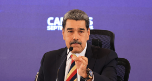 Nicolás Maduro falando em microfone e gesticulando, sério, sem olhar para a câmera, sentado