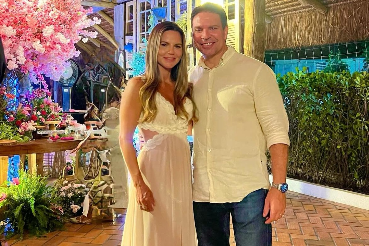 Rebeca Ramagem e Alexandre Ramagem posando lado a lado, em pé, sorrindo, de roupas brancas