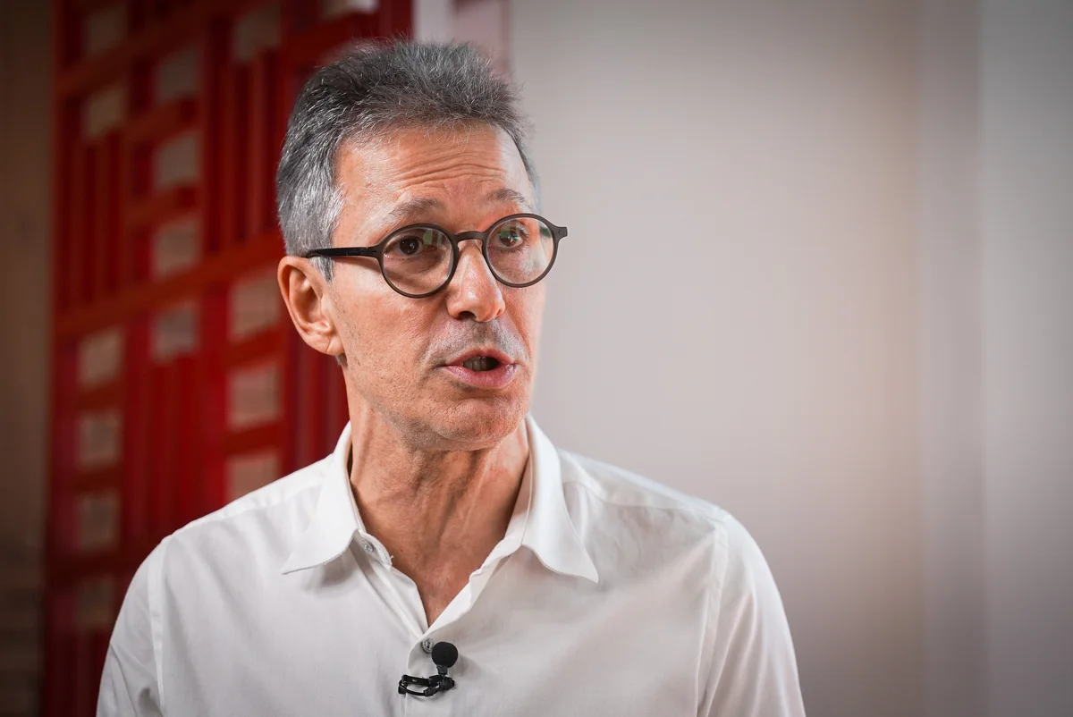 governador de Minas, Romeu Zema, de óculos de grau e camisa polo branca, falando sem olhar pra câmera