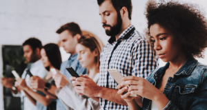 Pessoas enfileiradas mexendo no celular