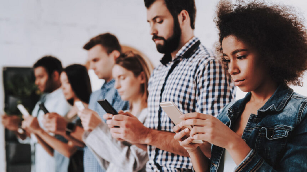 Pessoas enfileiradas mexendo no celular