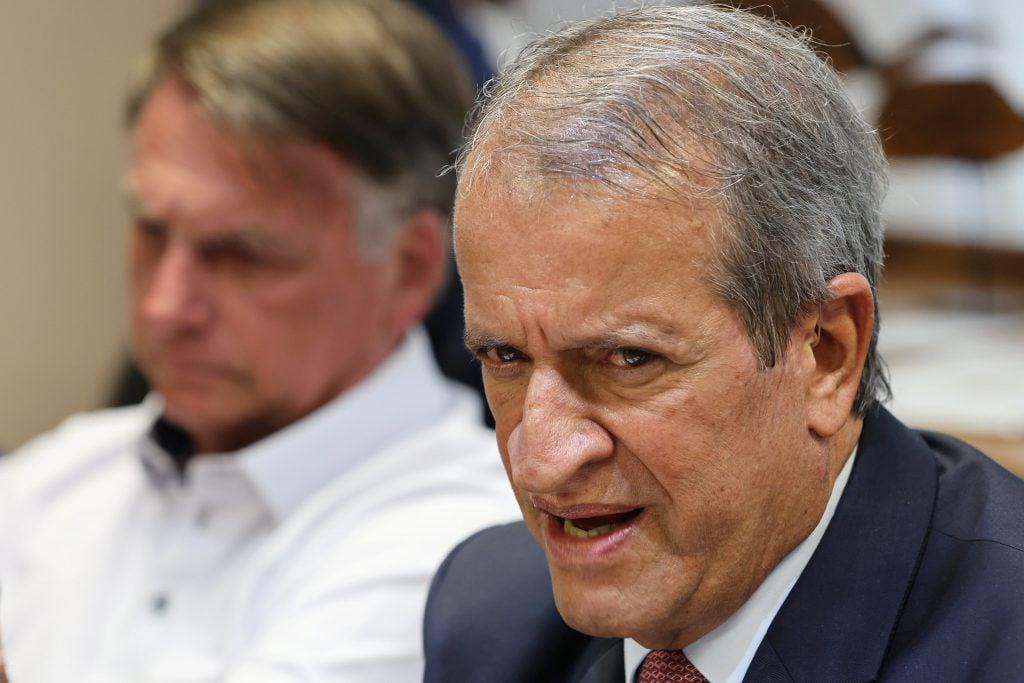 presidente do PL, Valdemar Costa Neto, em primeiro plano, falando e Jair Bolsonaro desfocado, sério, no fundo de foto