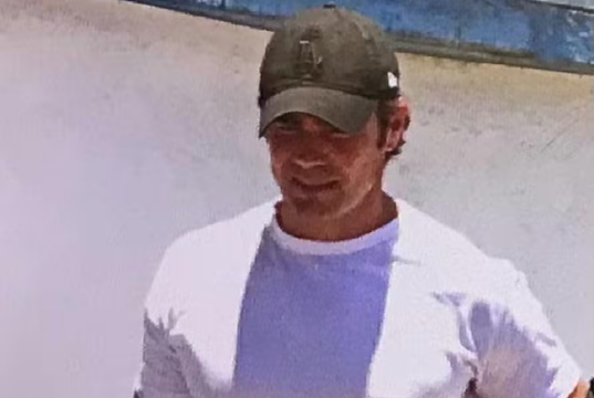 Vorcaro ao deixar a prisão, de cabeça baixa, de camiseta branca e boné verde, segurando Bíblia