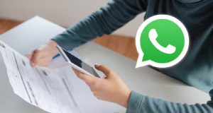 Pessoa tirando foto de papel com símbolo de whatsapp na imagem