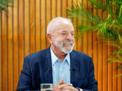 Lula olhando para o lado e sorrindo, sentado