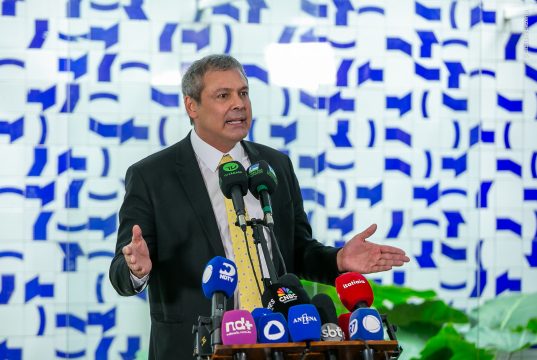 O deputado federal Lindbergh Farias (PT-RJ) em pé, perto de microfones, sério, gesticulando