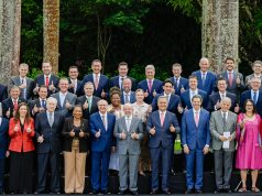 Lula e ministros em pé, sorrindo lado a lado e fazendo sinal de joia