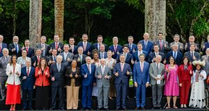 Lula e ministros em pé, sorrindo lado a lado e fazendo sinal de joia