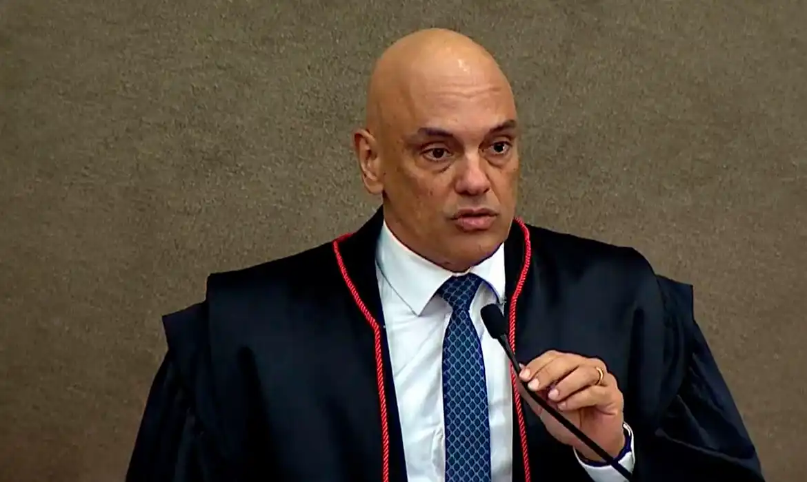 ministro Alexandre de Moraes falando em microfone, sério, sem olhar para a câmera