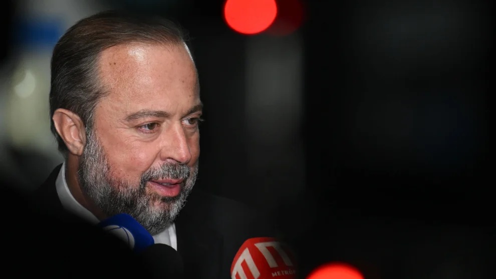 Alexandre Silveira no canto direito de foto, falando, em close, sem olhar para a câmera, sério