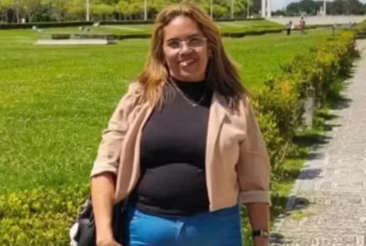 Lucinete Freitas sorrindo para a câmera, em pé, de cabelo solto, com roupa de frio