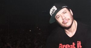 Chorão de camiseta e boné pretos, no canto direito de foto