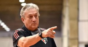 Cláudio Mortari, ex-técnico da seleção brasileira de basquete, sério, apontando pra frente sem olhar para a câmera, com camisa do SPFC