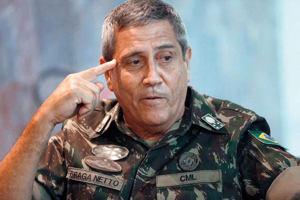 general Walter Braga Netto fardado, olhando para o lado com dedo apontado pra própria cabeça