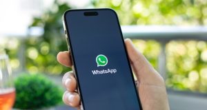 Mão segurando celular com a logo do WhatsApp