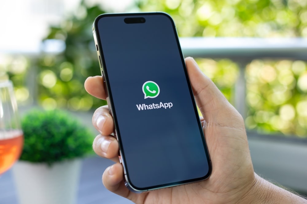 Mão segurando celular com a logo do WhatsApp