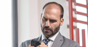 Eduardo Bolsonaro (PL-SP) mexendo no celular, de cabeça baixa, sério