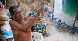 Alejandro Carranza, pai do pescador colombiano de mesmo nome que morreu, de bermuda cinza, sem camisa, segurando rede de pesca
