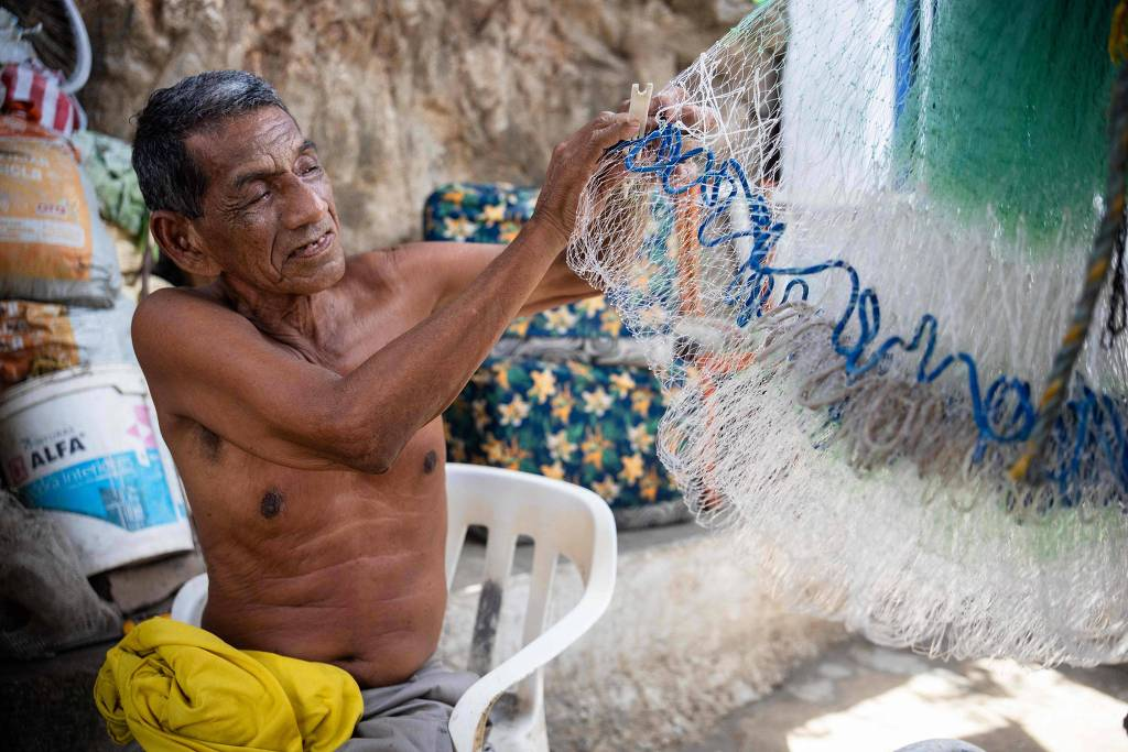 Alejandro Carranza, pai do pescador colombiano de mesmo nome que morreu, de bermuda cinza, sem camisa, segurando rede de pesca