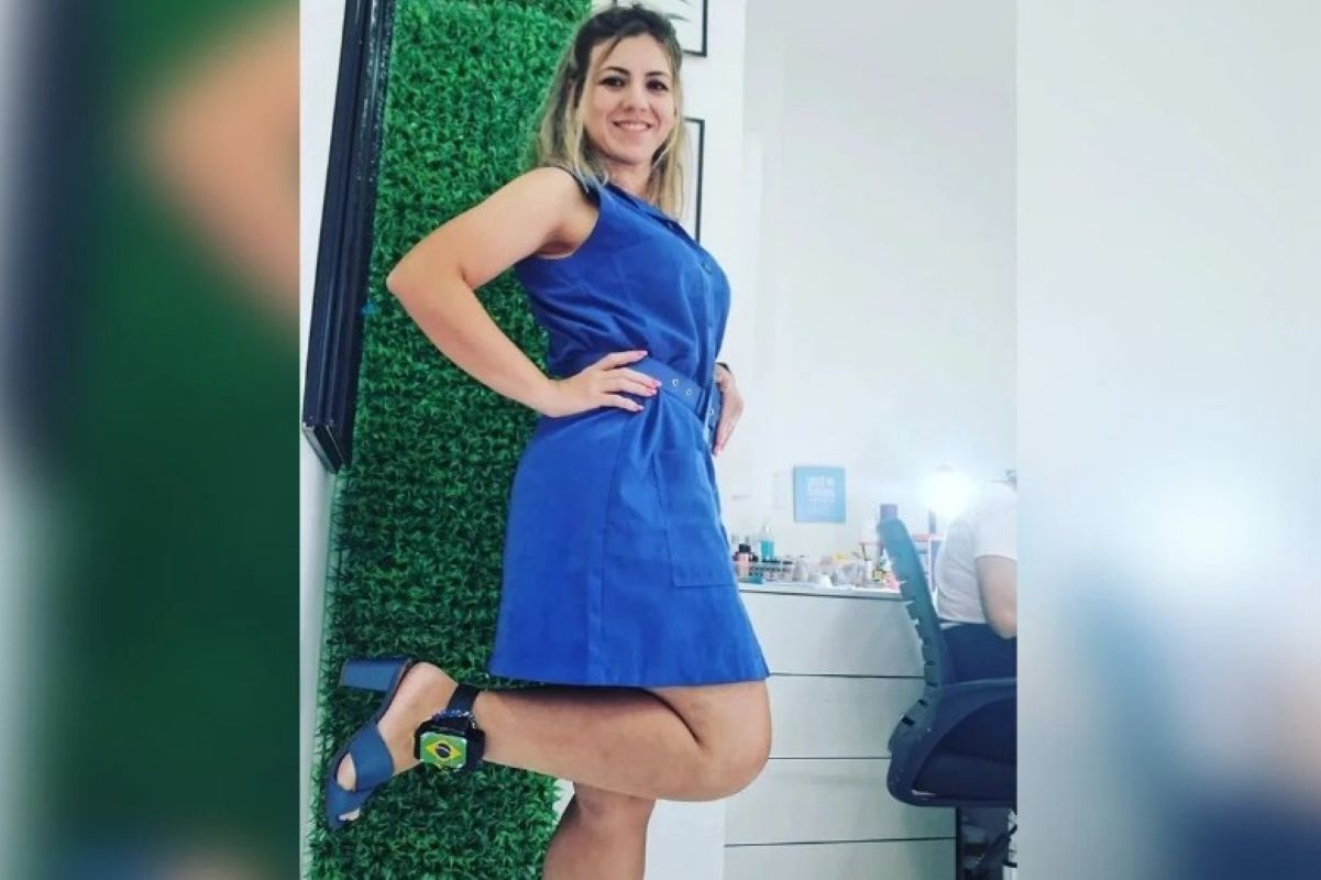 Roberta Jersyka Oliveira Brasil Soares, ex-aluna de medicina da USP, sorrindo, de vestido azul, mostrando tornozeleira eletrônica
