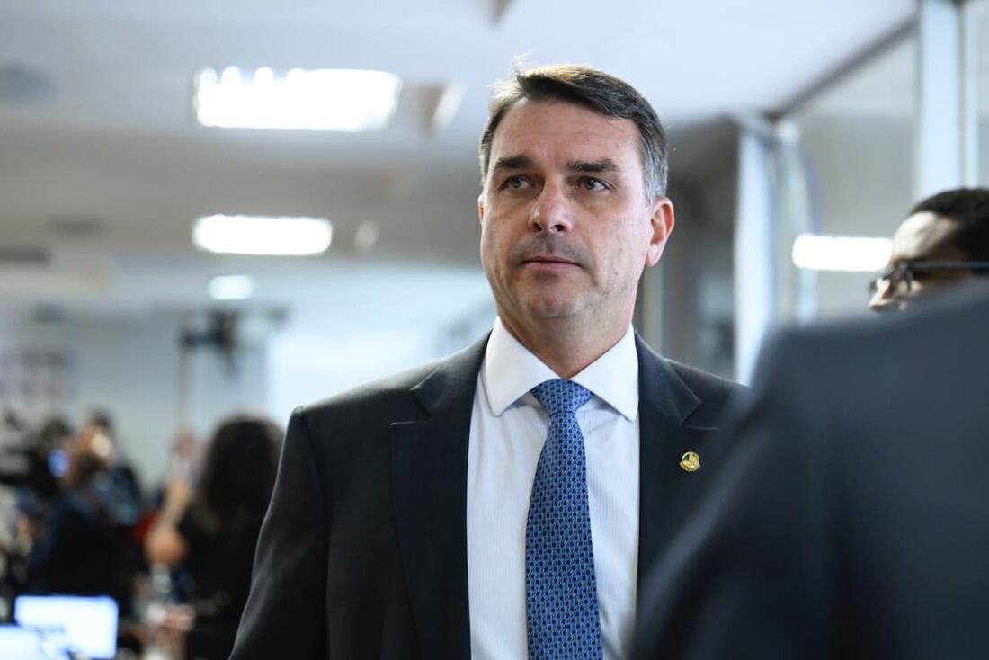 senador Flávio Bolsonaro (PL-RJ) sério, em pé, olhando levemente para o lado esquerdo da foto
