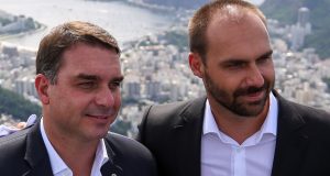 O senador Flávio Bolsonaro (PL-RJ) e o ex-deputado federal Eduardo Bolsonaro (PL-SP) em close, lado a lado, sem olhar para a câmera