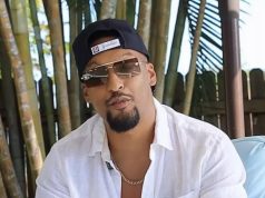 O influenciador bolsonarista Alex Oliveira de boné para trás, óculos escuros e camisa social branca, sério, falando para a câmera