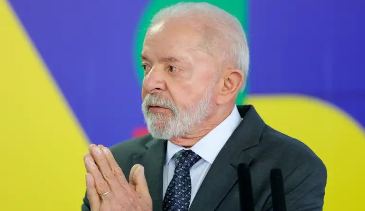 Lula sério, olhando para o lado, com as mãos unidas