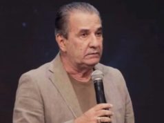 pastor Silas Malafaia de roupa social bege, olhando para o lado, sério, segurando microfone