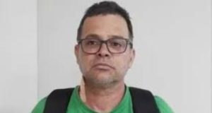 ex-diretor-geral da PRF (Polícia Rodoviária Federal) Silvinei Vasques de camiseta verde, óculos e mochila preta nas costas, olhando para a câmera, sério