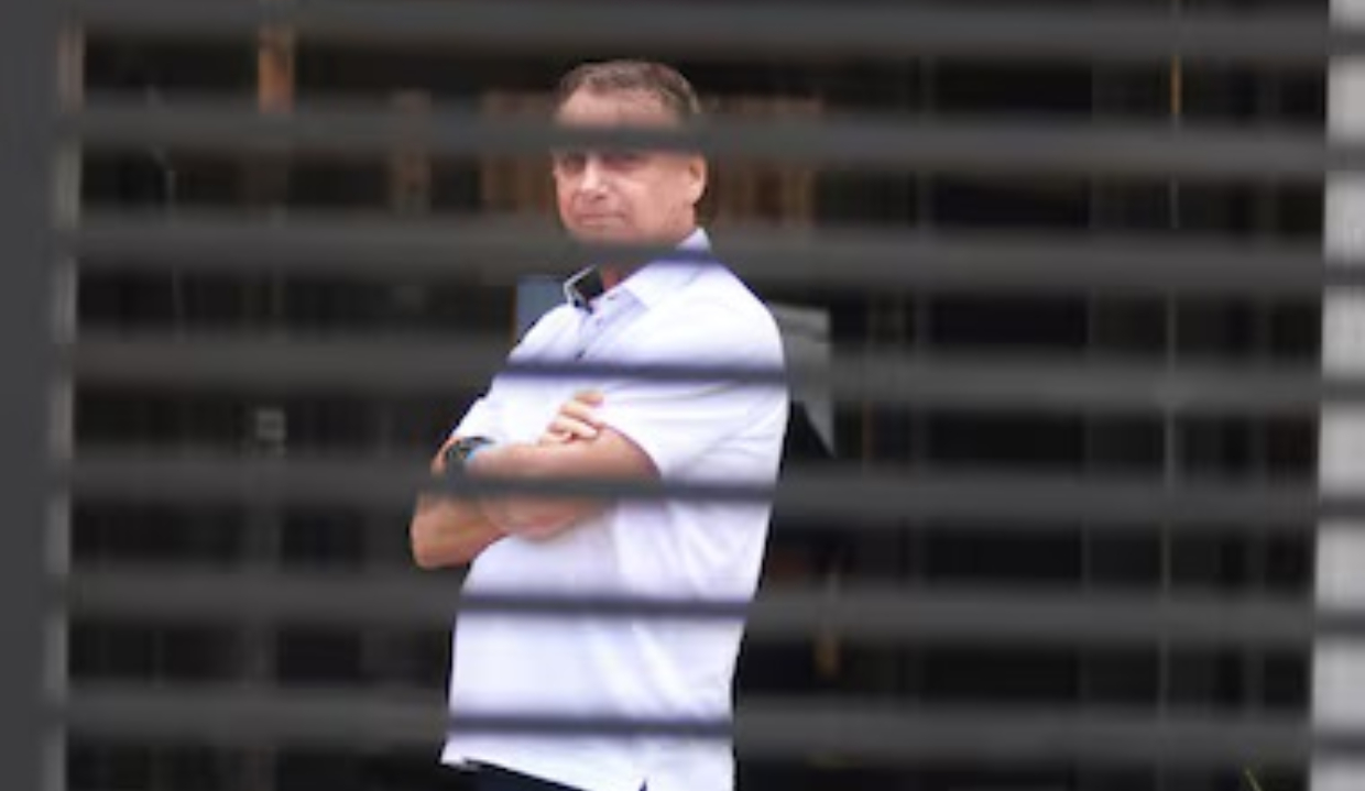 Ex-presidente Jair Bolsonaro em prisão domiciliar, de camisa branca e braços cruzados