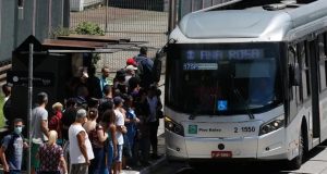 pessoas em ponto de ônibus lotado