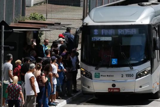 pessoas em ponto de ônibus lotado