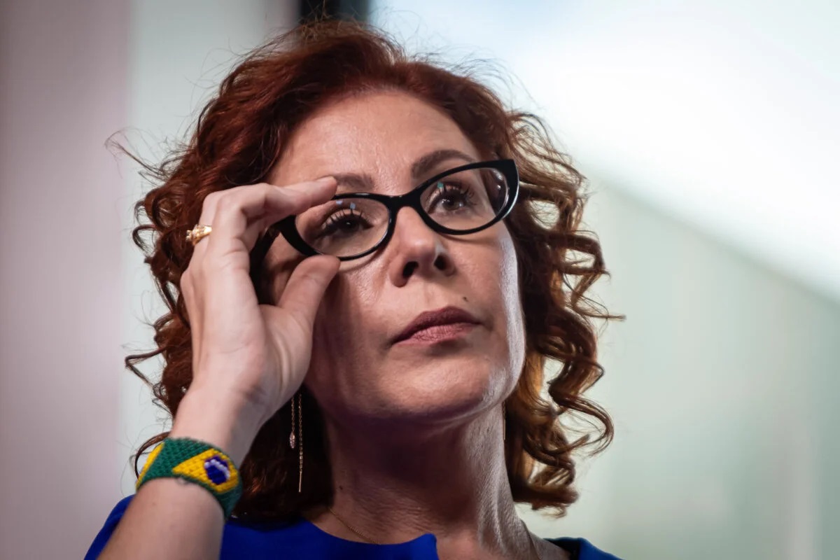 Carla Zambelli séria, mexendo em óculos de grau