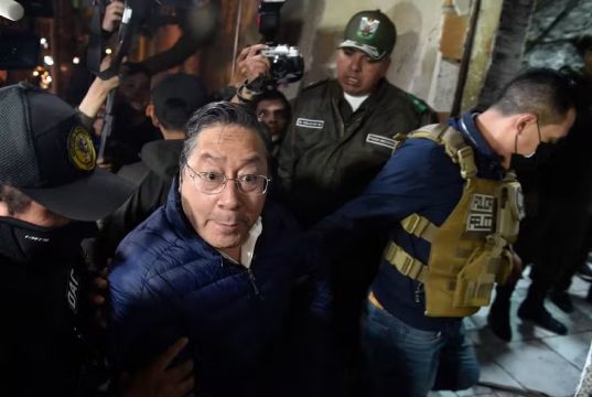 Luis Arce, ex-presidente da Bolívia, sendo escoltado por policiais após audiência
