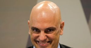 Alexandre de Moraes, ministro do STF, sorrindo, em close, olhando para a câmera