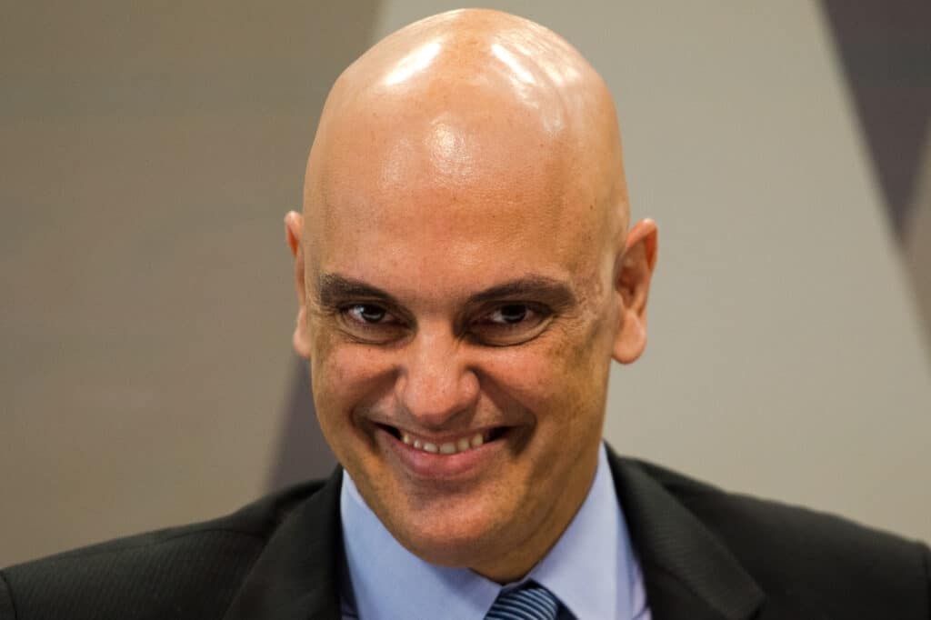 Alexandre de Moraes, ministro do STF, sorrindo, em close, olhando para a câmera